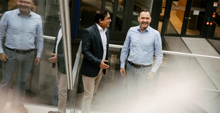 Edward Aston und ein Kollege stehen in einem Treppenhaus. 